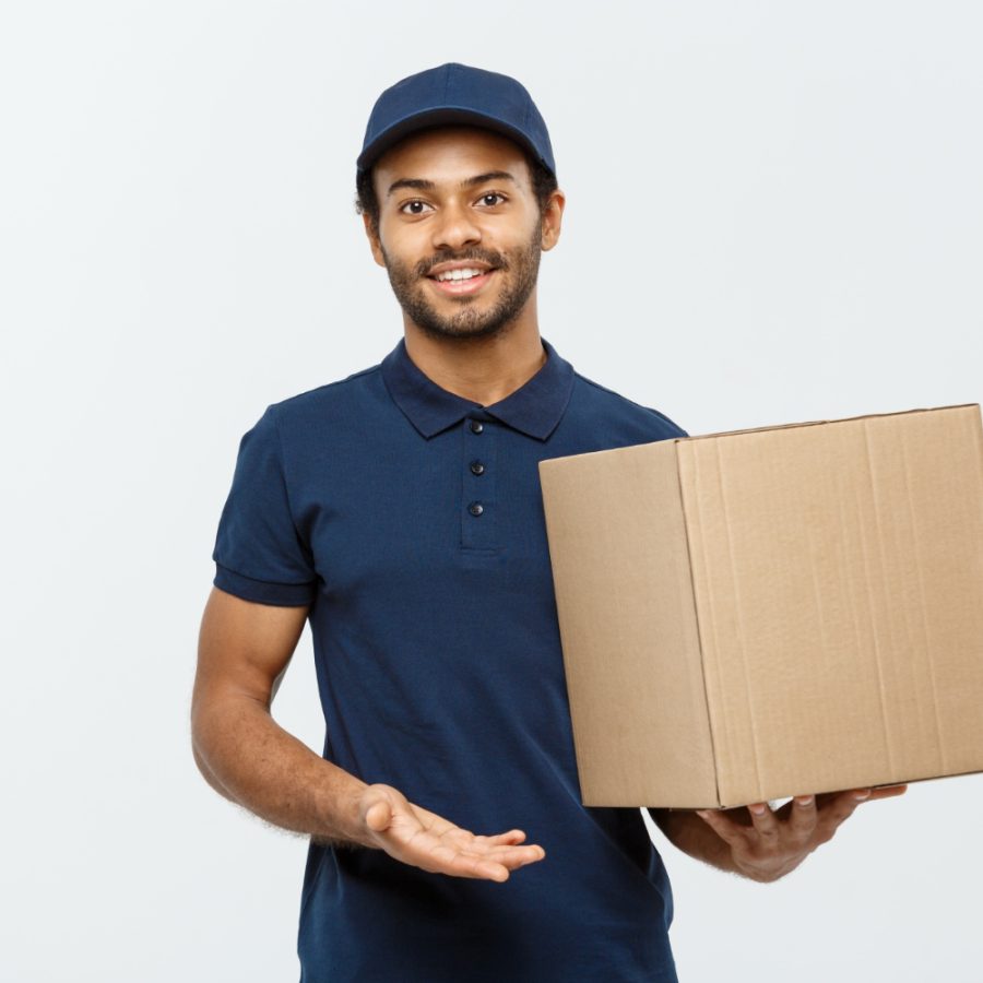 delivery-concept-portrait-happy-african-american-delivery-man-red-cloth-holding-box-package-isolated-grey-studio-background-copy-space delivery-concept-portrait-happy-african-american-delivery-man-red-cloth-holding-box-package-isolated-grey-studio-background-copy-space